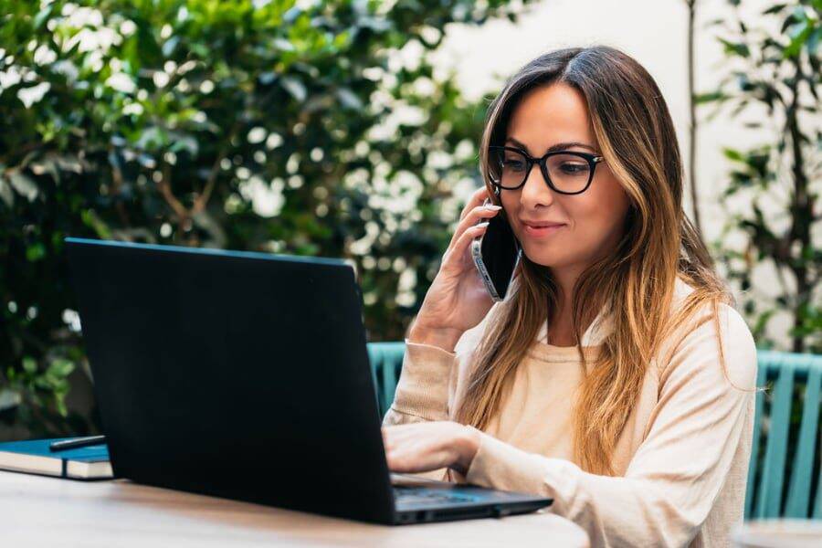 Woman Outdoors On Phone With Laptop 900x600