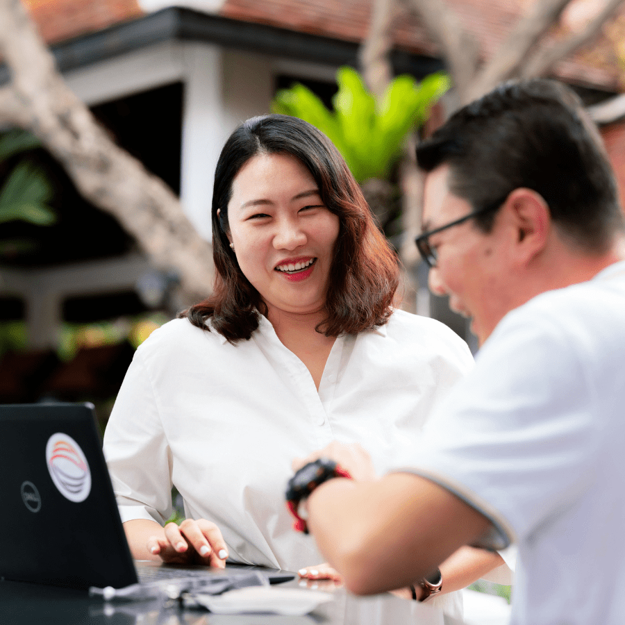 Asian woman and man talking in front of a laptop