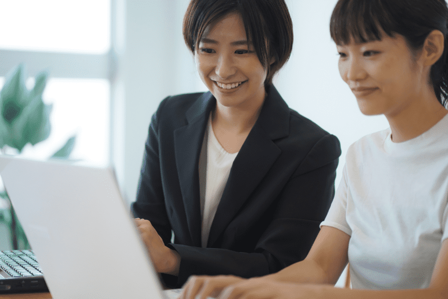 two female Japanese colleagues working together in front of a laptop