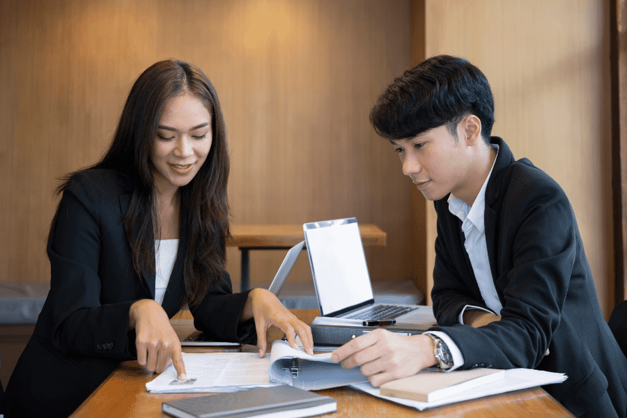 two HR managers working with a laptop and paperwork on the table